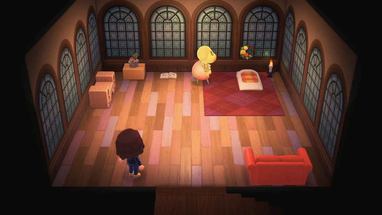 A light orange room from Animal Crossing new horizons. There are large windows with rounded tops all over the walls and it is dark outside. There is a futon with a candle on top of a red carpet. Next to it is a dog-character sitting in a peach shaped seat. A cat is sleeping on the futon